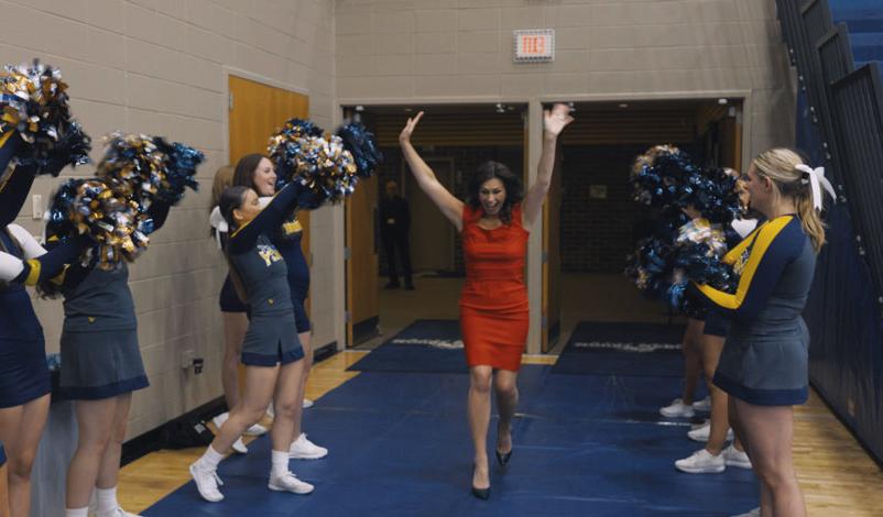 Stefanie Munsterman, Mount Mercy alumni award recipient, running through cheerleaders with her arms raised