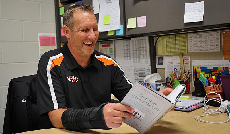 Brad, reading "The Ideal Team Player" and smiling at his desk